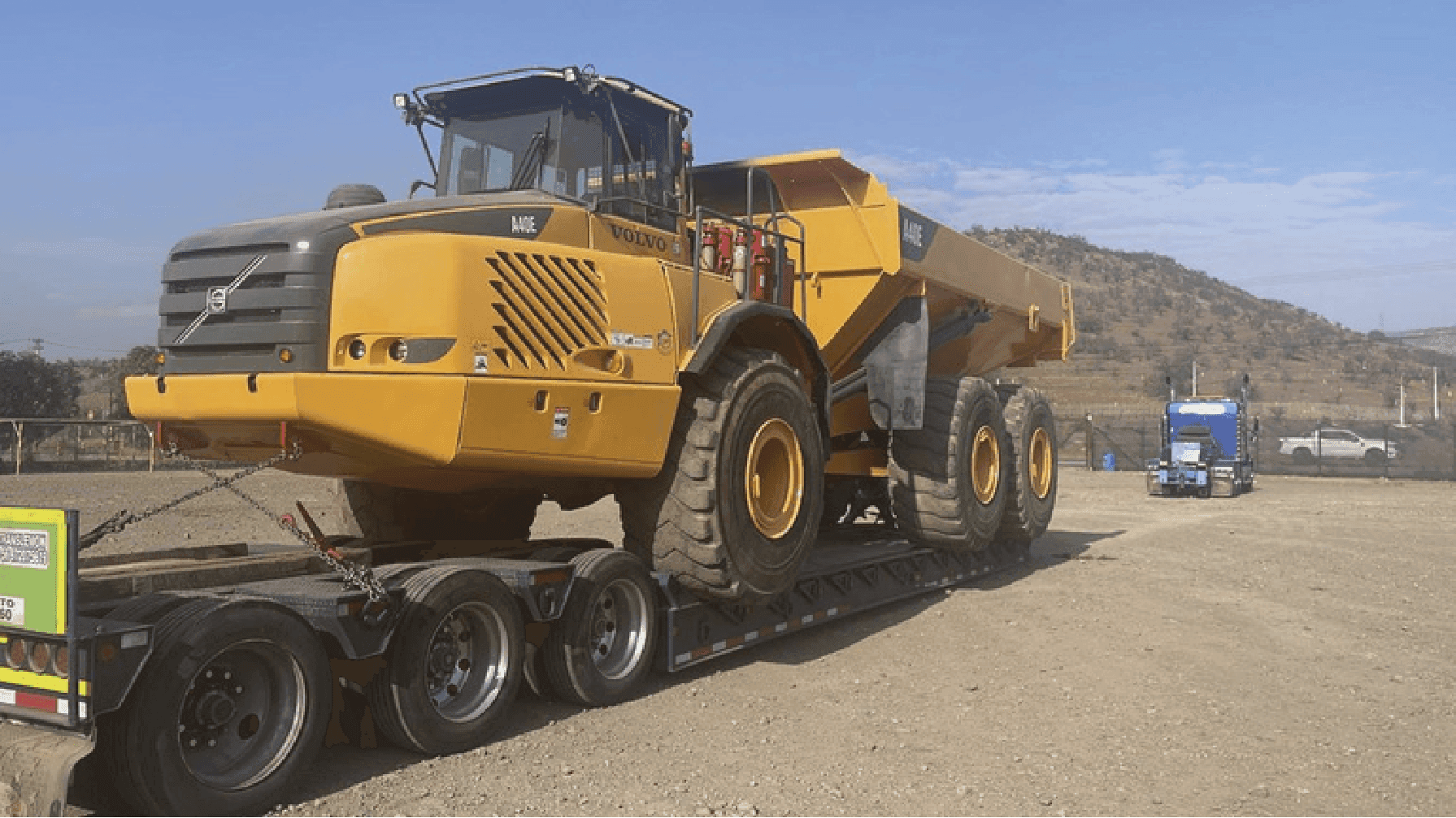 Volquete articulado en transporte sobre plataforma baja.
